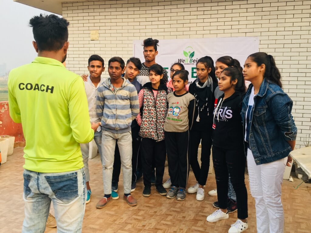 A coach briefing young participants during a Well Being Foundation sports session
