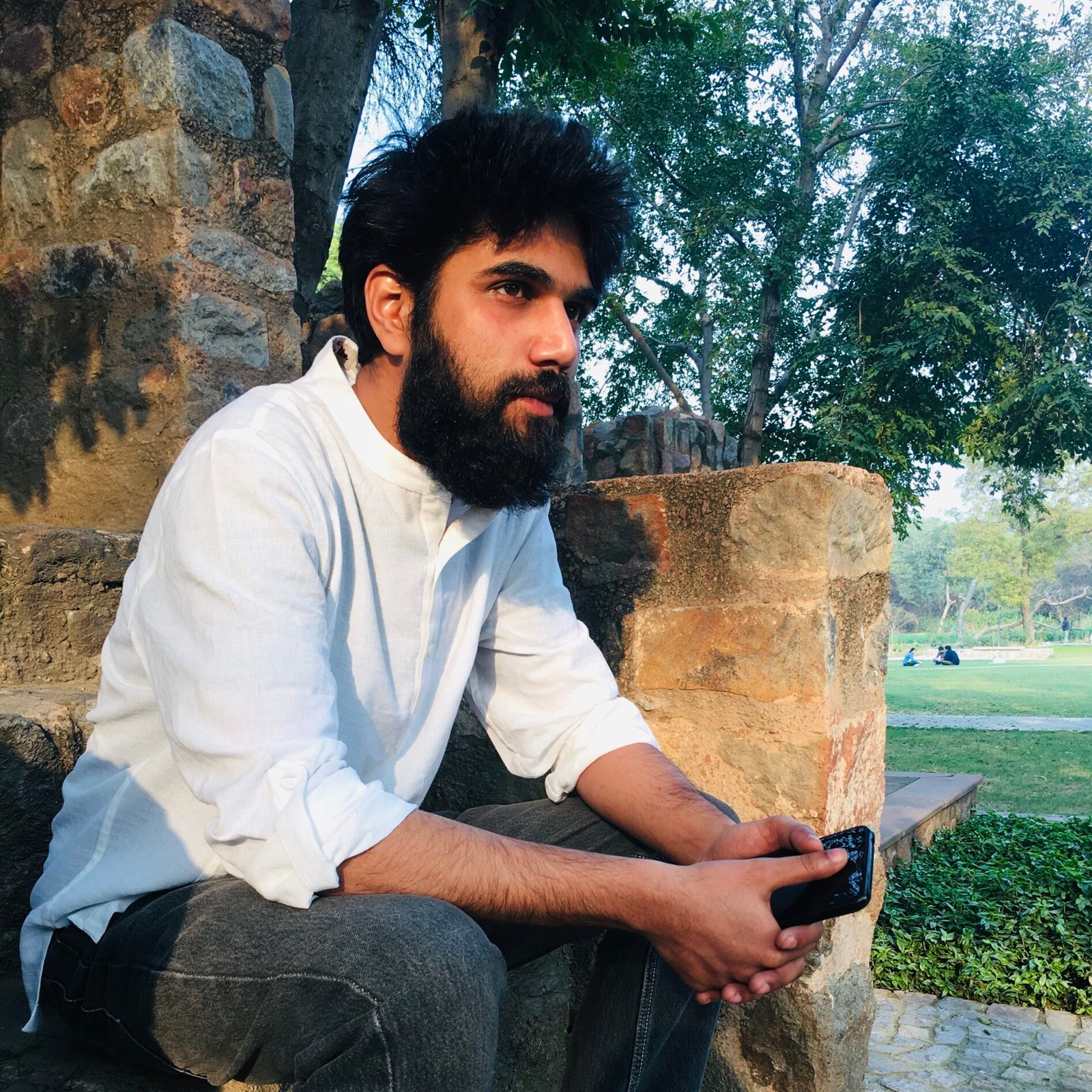 Community member sitting in a park with trees in the background
